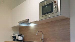 Una cocina moderna con armarios blancos, un microondas de acero inoxidable, un lavamanos con grifo moderno y una encimera de madera.