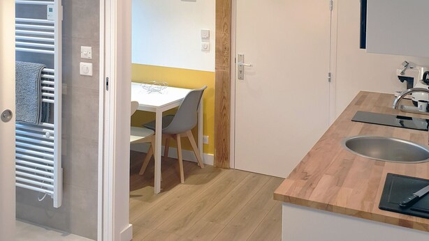 Una cocina moderna con encimera de madera, un fregadero y un comedor con mesa y sillas.