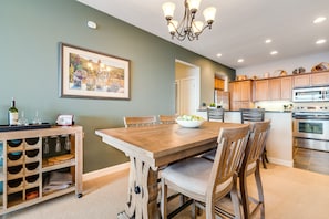 A dining area with a wooden table and chairs, a wine rack, and a framed picture on the wall.