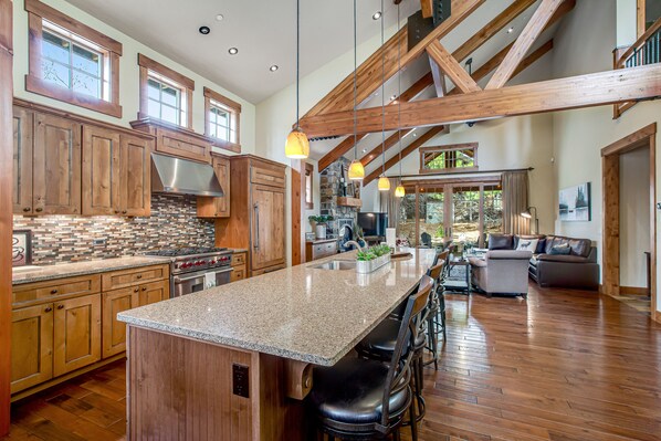 A spacious kitchen with granite countertops, wooden cabinets, and a large island with bar stools.