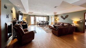 Amplia sala de estar con chimenea, televisor, sofá y mesa de comedor con sillas.