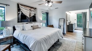 A modern bedroom with a large bed, a ceiling fan, and a view of the bathroom. - Lake views from The Byrd House (Pottsboro)