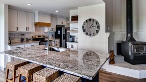 A modern kitchen with white cabinets, a granite countertop, a built-in stove, and a clock on the wall. - Lake views from The Byrd House (Pottsboro)