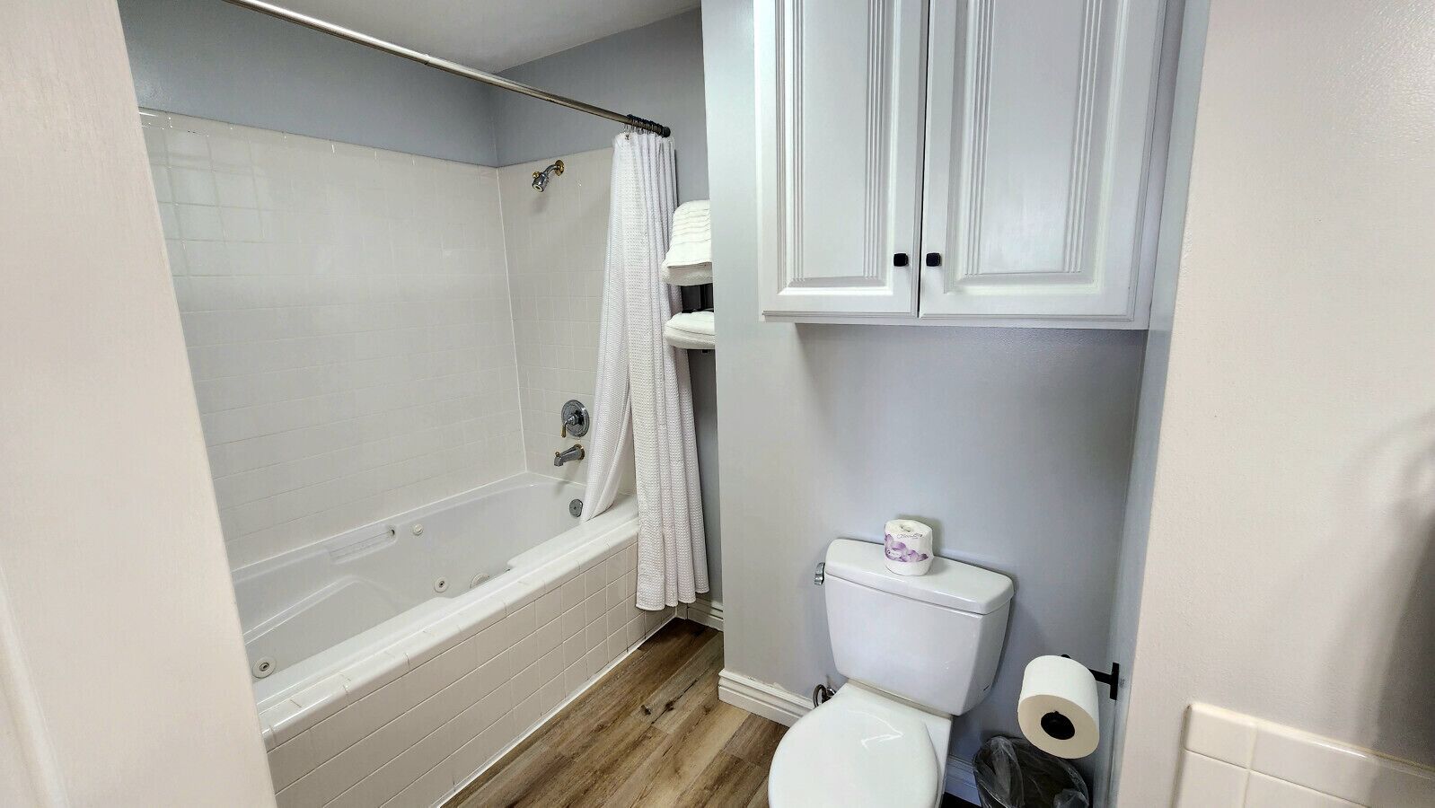 Une salle de bain avec une baignoire, des toilettes et des meubles blancs.