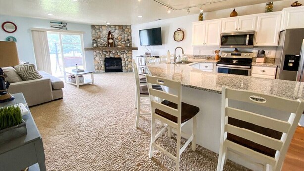 Een moderne keuken met granieten werkbladen, witte kasten en een centraal eiland met barstoelen.