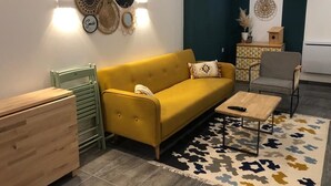 Una sala de estar moderna con un sofá amarillo, una mesa de centro de madera y una alfombra estampada.
