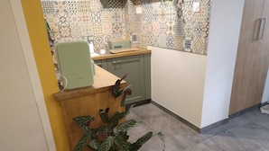 Una cocina con baldosas estampadas, encimera de madera, una silla verde y una planta en maceta.