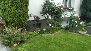 Een verzorgde tuin met verschillende bloeiende planten en een strak gemaaid gazon voor een gebouw.