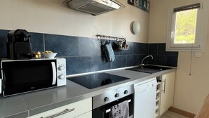 A compact kitchen with a microwave, stove, oven, and a window. - Near Paimpol, duplex Beach Bréhec 200m (Plouézec)