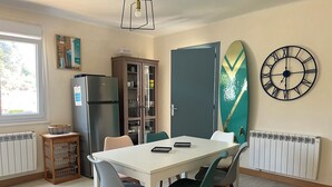 A dining area with a white table, four chairs, a refrigerator, a cabinet, and a clock on the wall. - Near Paimpol, duplex Beach Bréhec 200m (Plouézec)