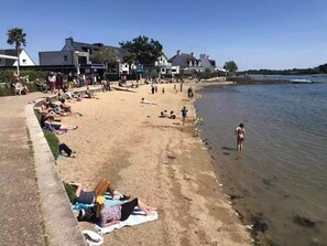 Ein Strand mit badenden Menschen und Spaziergängern am Ufer.