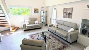 Ein geräumiges Wohnzimmer mit zwei Sofas, einem Couchtisch und einer Vitrine. Im Hintergrund ist eine Treppe zu sehen.
