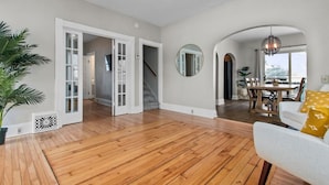 A spacious living area with wooden flooring, a staircase, and a dining area with a table and chairs.