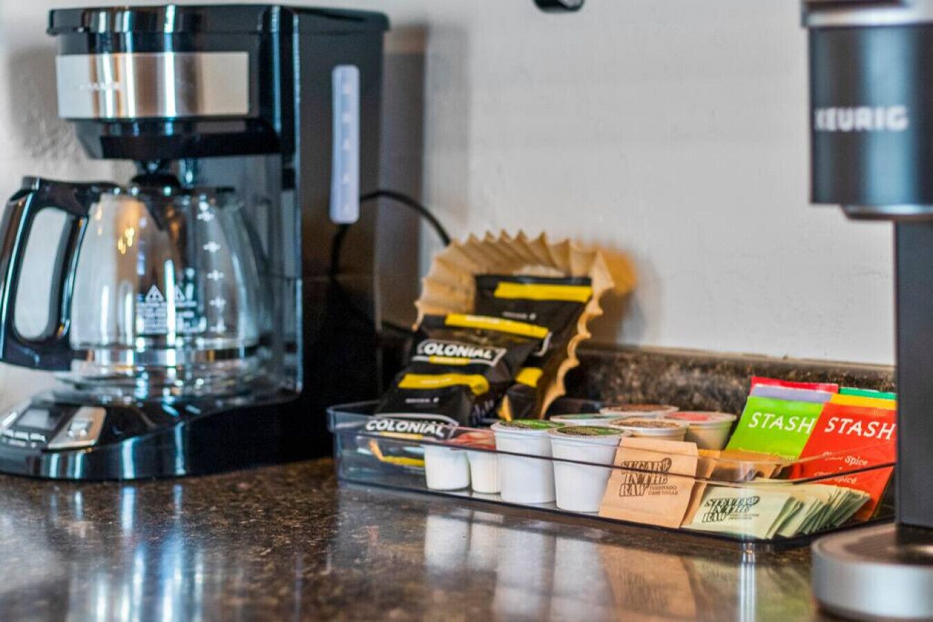 A coffee machine, a coffee grinder, and a variety of coffee pods and capsules on a countertop.