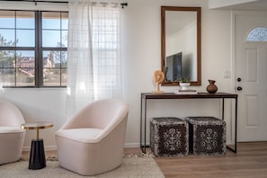 A room with a large window, a round table, two chairs, a mirror, and a door. - Spacious Modern Home in Sedona! (Sedona)