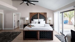 A bedroom with a bed, a ceiling fan, a large window, and a door. - Paradise Palace-Heated Pool/Spa-Guest House & More (Scottsdale)