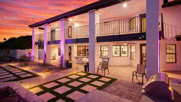 A two-story house with a covered patio, outdoor seating, and a well-lit entrance. - Paradise Palace-Heated Pool/Spa-Guest House & More (Scottsdale)