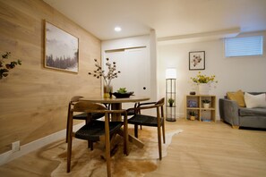 Un coin repas avec une table et des chaises en bois, un vase rempli de fleurs et un tableau accroché au mur.
