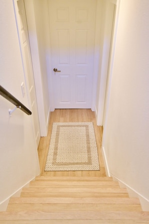 A staircase with a wooden floor leading to a white door with a door handle. - Cozy Private Retreat Near University of Denver (Denver)