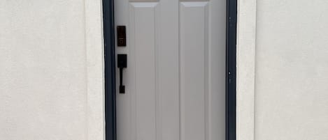 A white door with a black frame, a small window above it, and a light fixture on the wall to the left.