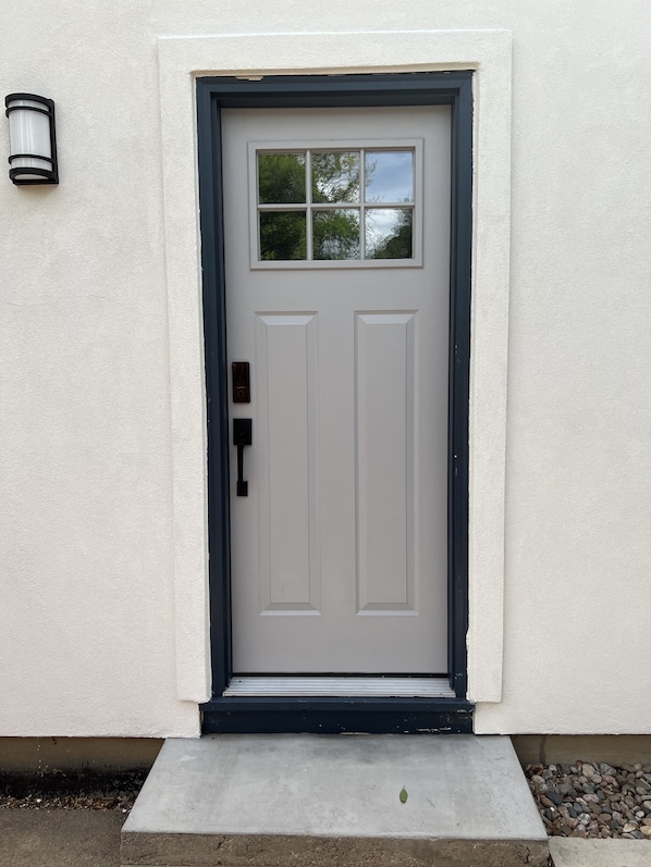 A white door with a black frame, a small window above it, and a light fixture on the wall to the left. - Cozy Private Retreat Near University of Denver (Denver)