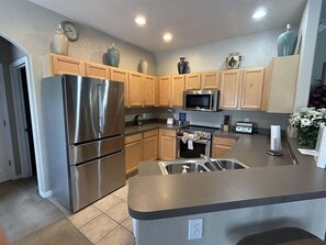 A modern kitchen with stainless steel appliances, wooden cabinets, and a granite countertop.