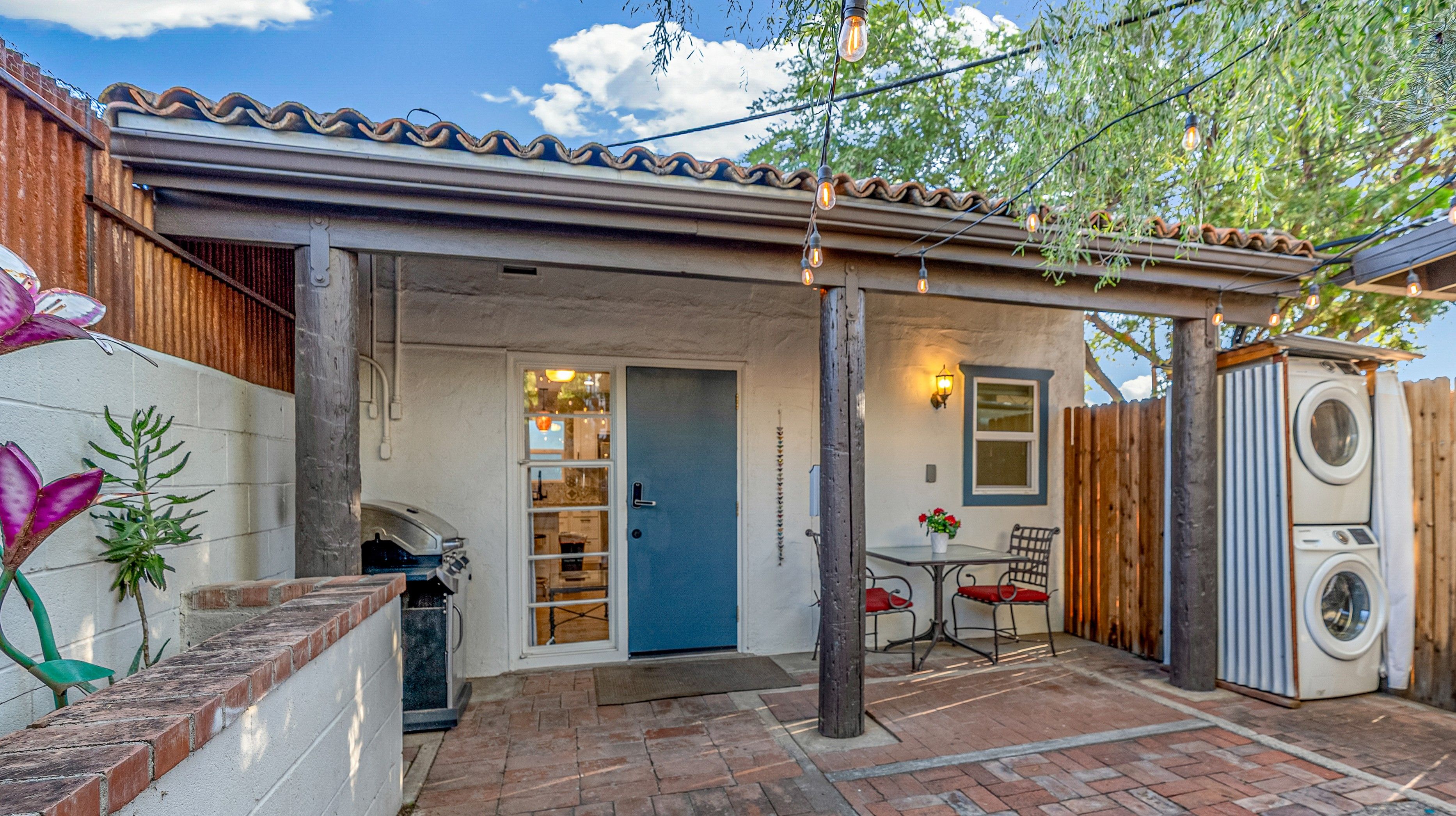 A patio area with a blue door, a washing machine, and a table with chairs.