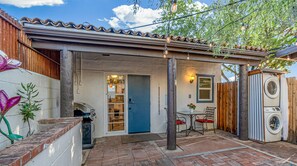 A patio area with a blue door, a washing machine, and a table with chairs.