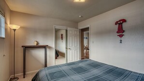 A bedroom with a bed, a bedside table, a lamp, and a door leading to another room.