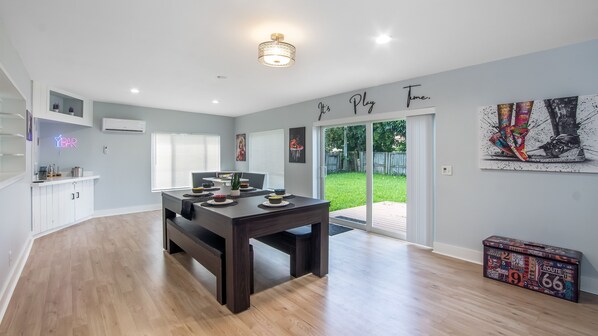 Cozinha moderna com mesa de madeira escura, armários brancos e um letreiro neon.