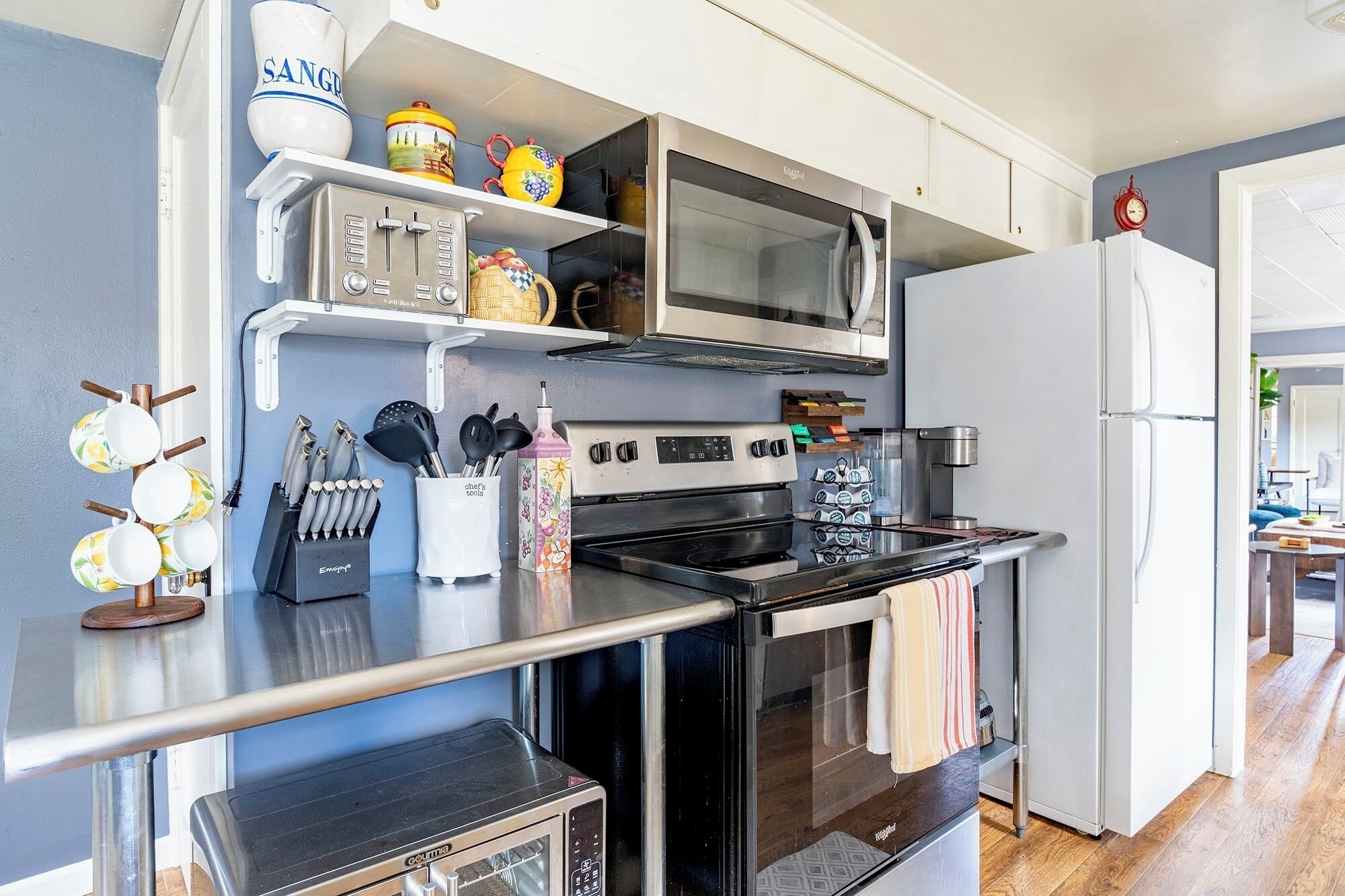 A kitchen with a microwave, stove, oven, and refrigerator. There are utensils and a coffee maker on the counter.