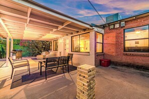 Une terrasse extérieure couverte, équipée d’un barbecue, de sièges et d’un mur en briques.