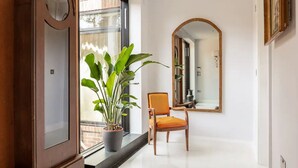 A hallway with a potted plant, a wooden chair, and a mirror on the wall. - Highgate - Luxury 4-Bedroom Spacious House with Indoor Pool (London)