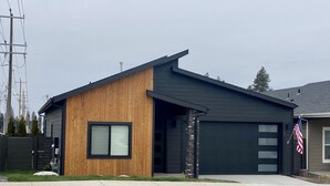 A modern two-story house with a garage, a wooden exterior, and an American flag. - Clean, Comfortable, and Modern CDA Retreat inside Gated Community. (Coeur d'Alene)