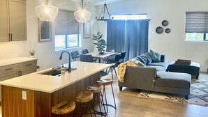 A modern kitchen with a central island, bar stools, and pendant lighting. - Clean, Comfortable, and Modern CDA Retreat inside Gated Community. (Coeur d'Alene)