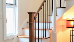 A staircase with wooden steps and black balusters, white walls, and a framed picture on the wall. - Stream Come True! Ski, hike, spa, flow, relax... (Chichester)
