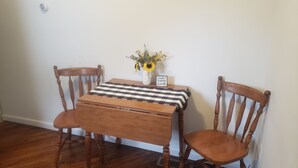 A wooden dining table with a checkered tablecloth, two wooden chairs, a vase with flowers, and a sign that says "make today lovely".