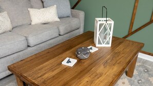 Une table basse en bois, avec un jeu de cartes et une lanterne, dans un salon.