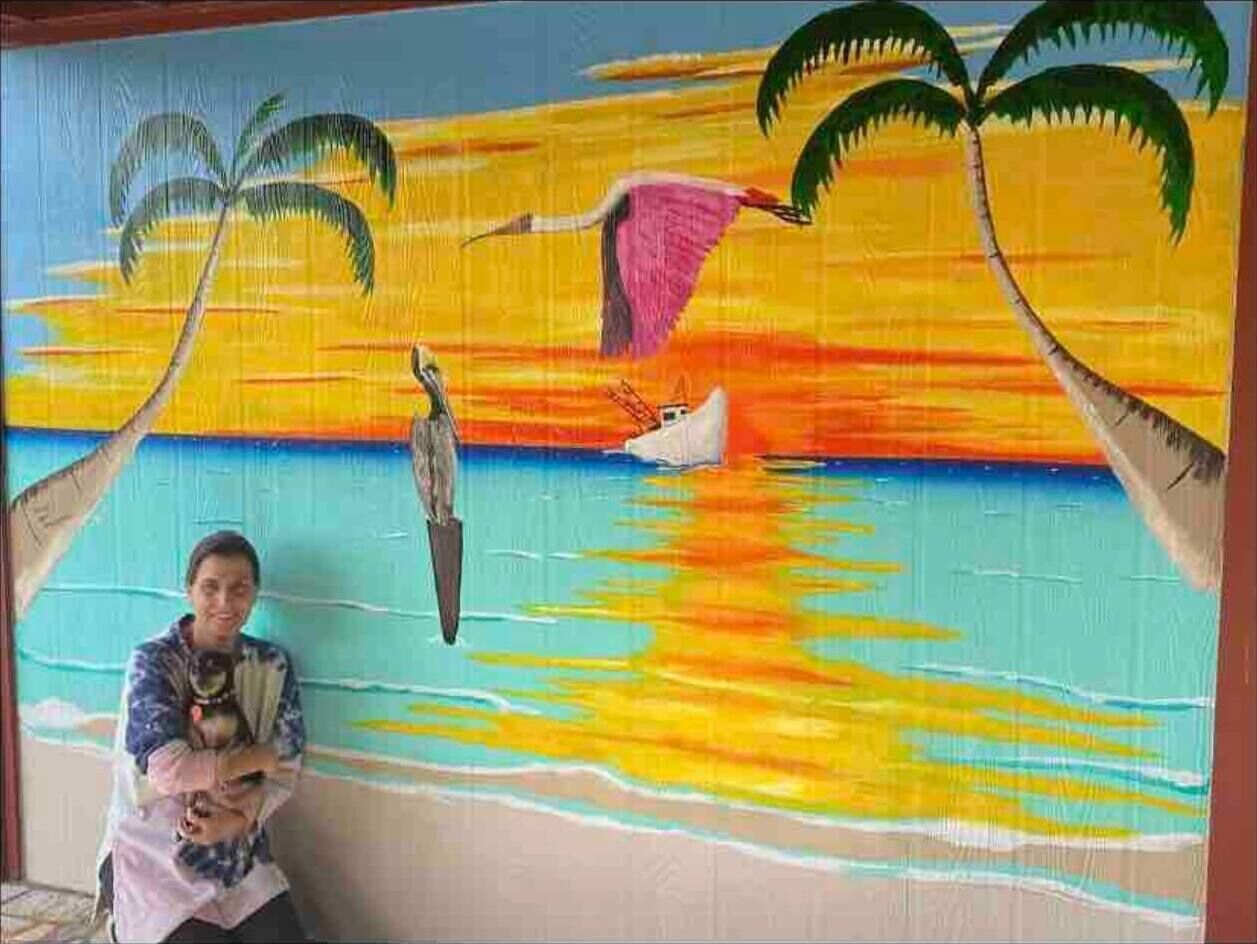 A mural of a tropical beach scene with palm trees and a bird.