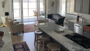 Una cocina amplia con una isla grande, taburetes de bar y un comedor con sofá y sillas.