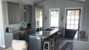 Una cocina moderna con armarios grises, una isla central con taburetes y un ventanal grande.