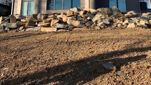 Una casa moderna de dos pisos con una terraza grande y cimientos de piedra.