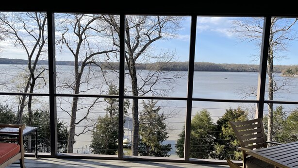 Una terraza de madera con vista a un lago y árboles.