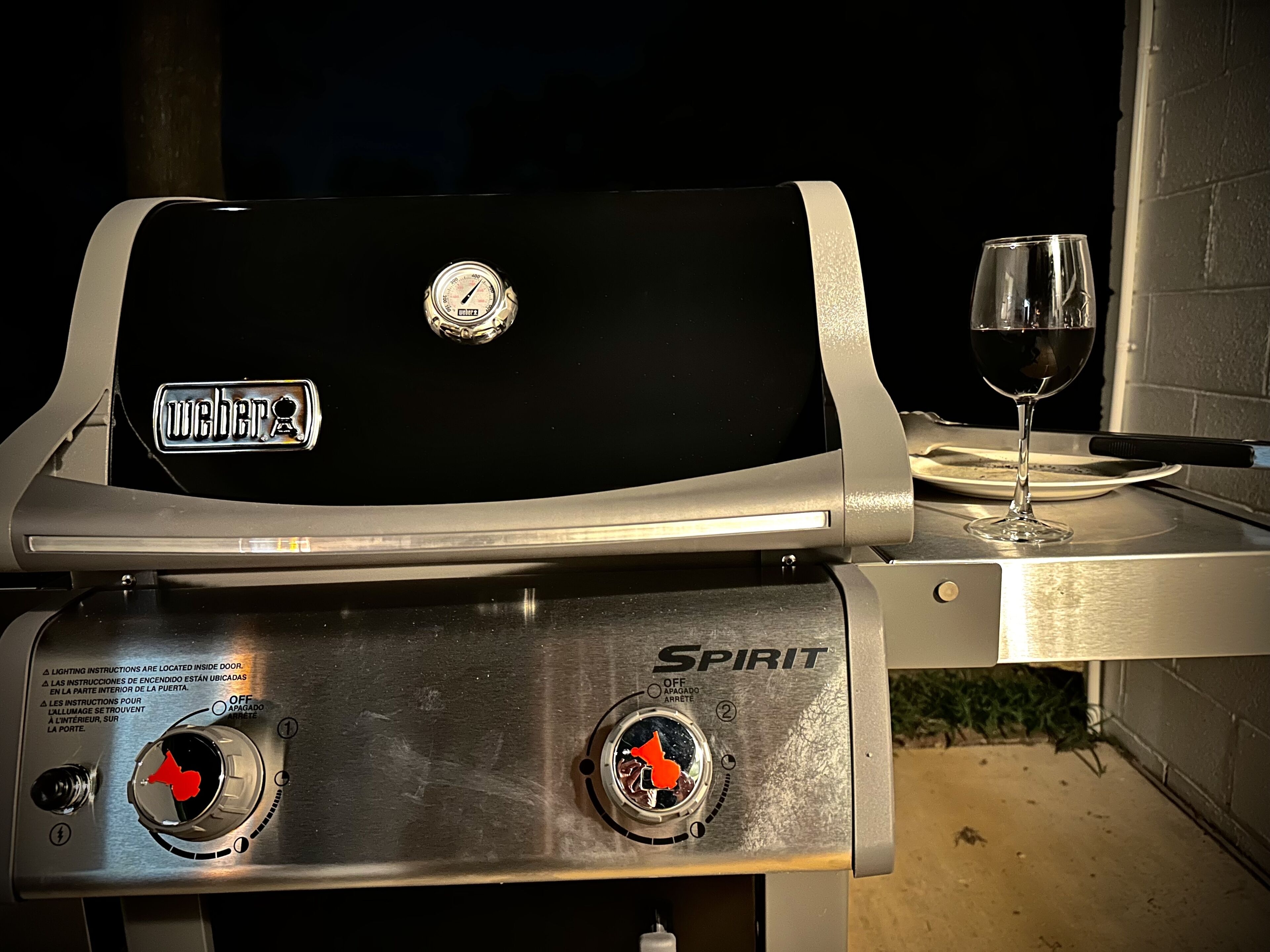 Un barbecue Weber Spirit avec un verre à vin à côté.