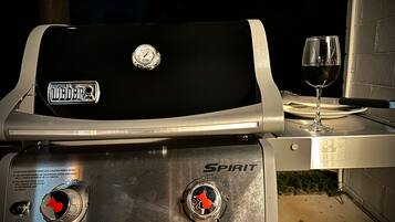 Un barbecue Weber Spirit avec un verre à vin à côté.