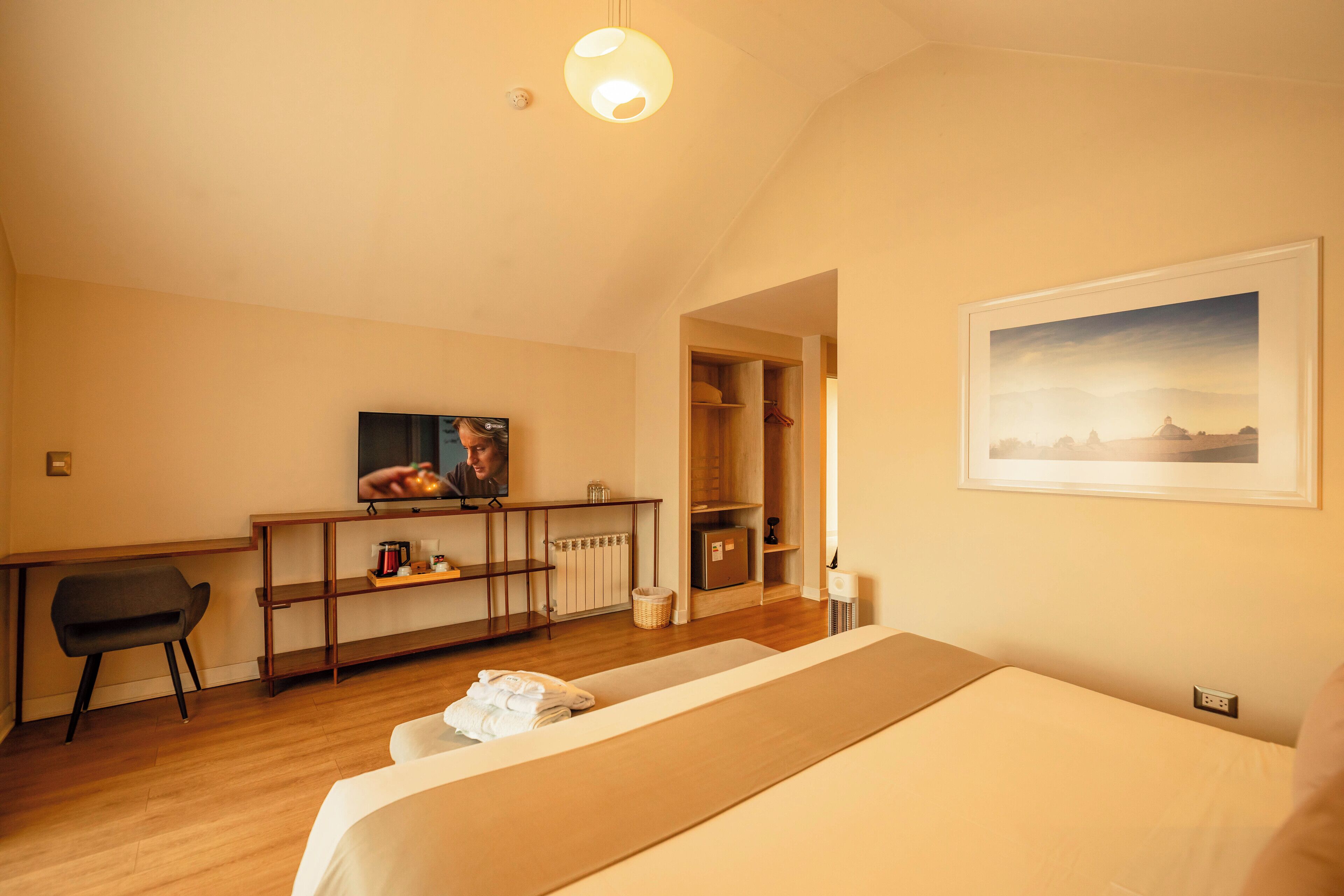 Camera d'albergo con un letto, una scrivania, una televisione e un quadro appeso al muro.