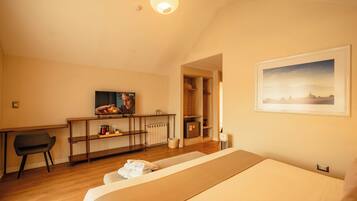 Camera d'albergo con un letto, una scrivania, una televisione e un quadro appeso al muro.