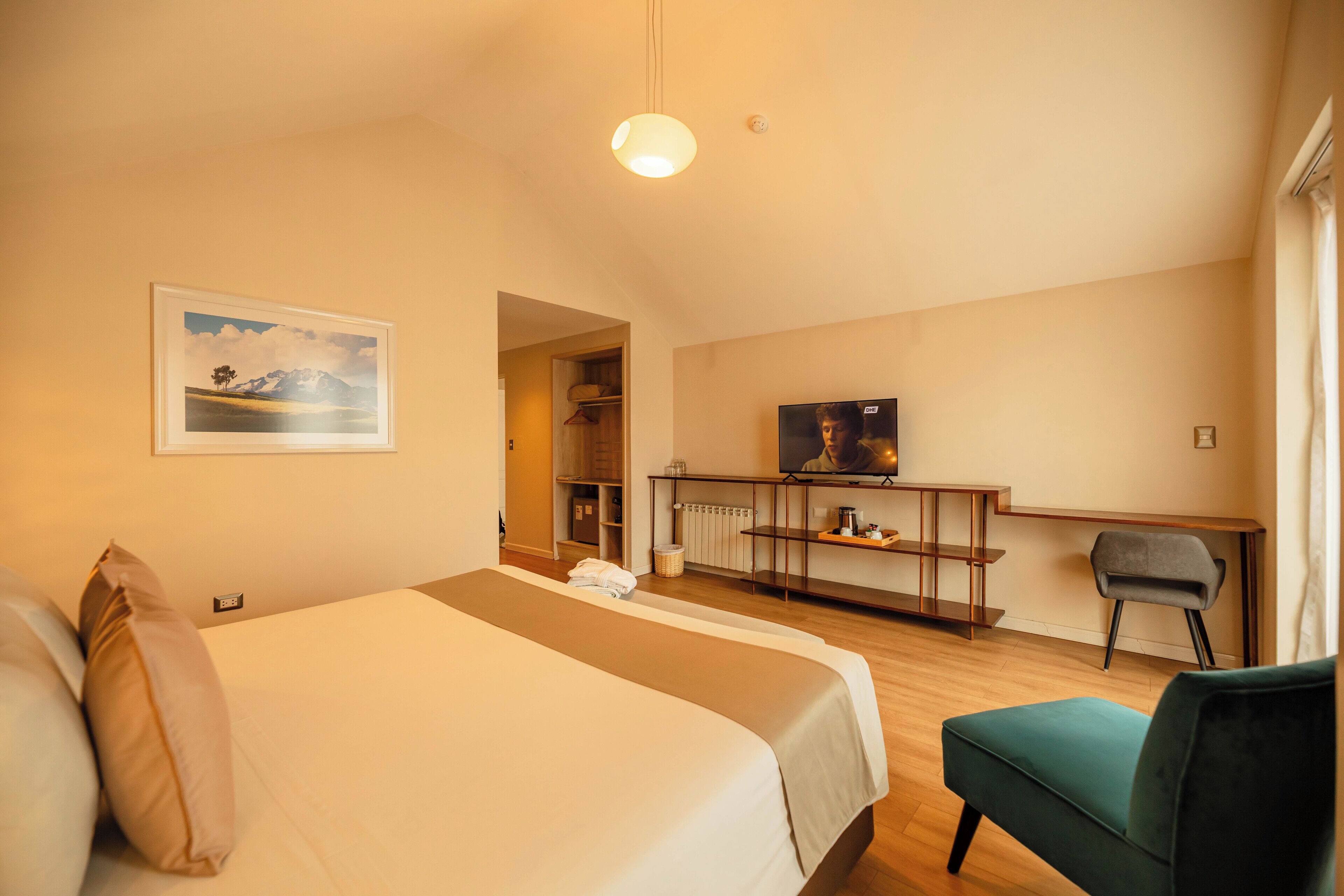 Una habitación de hotel con una cama, un escritorio, una silla y un televisor.