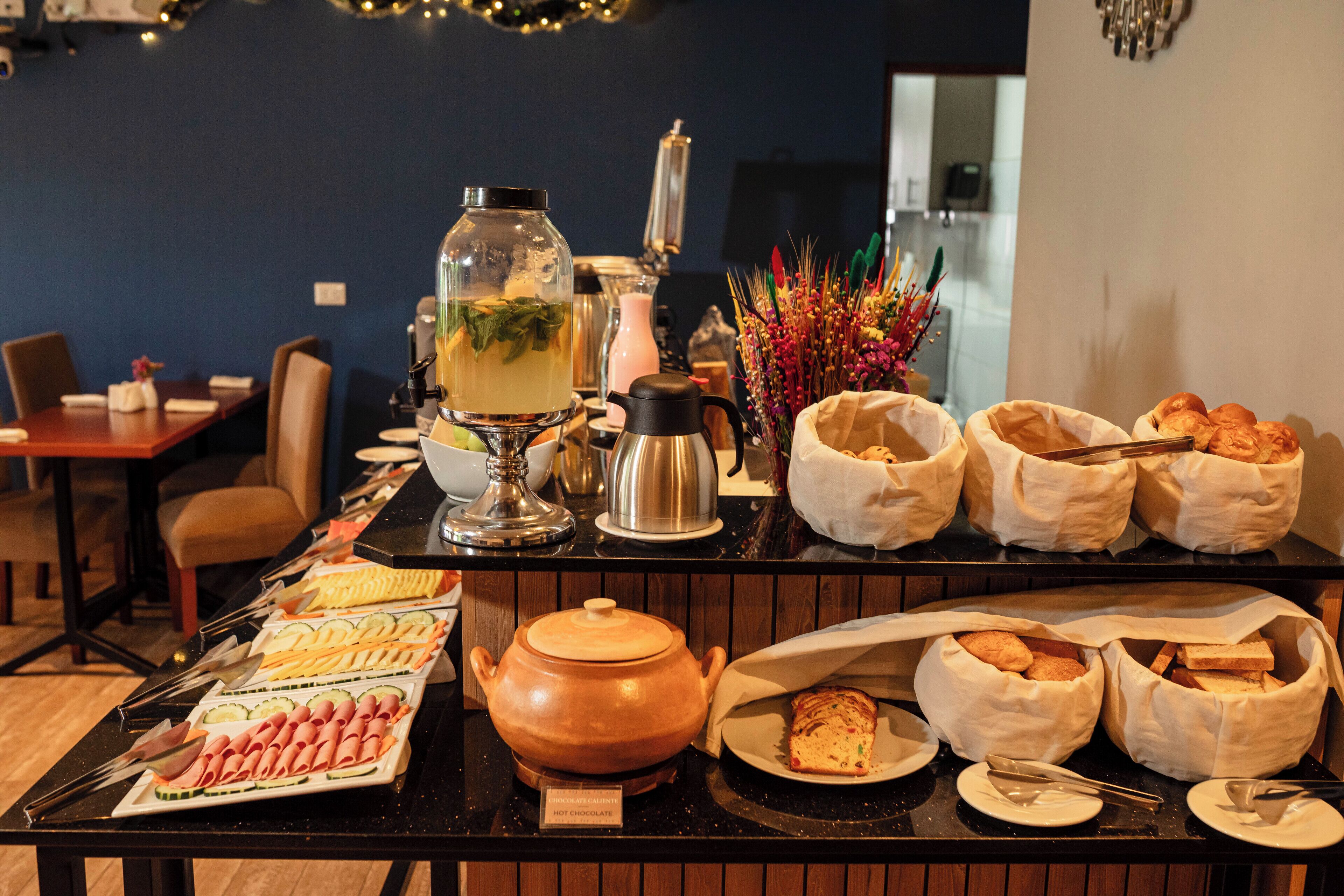 Una mesa de buffet con diversos alimentos, una tetera y elementos decorativos.