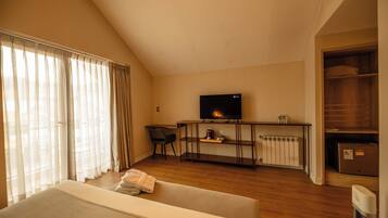 A hotel room with a bed, a desk with a chair, a television, and a radiator.